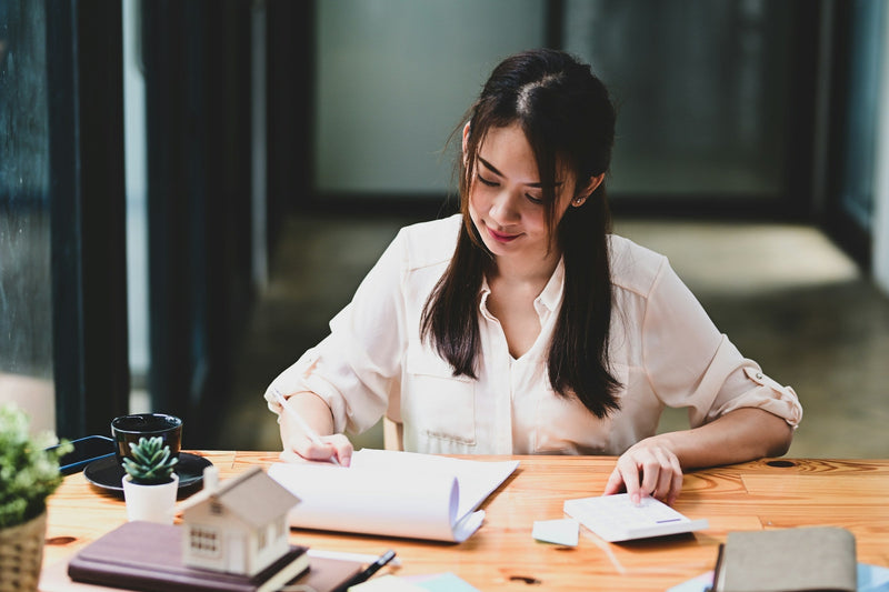 A businesswoman planning at a desk with a laptop and notebook, representing the strategic planning involved in launching a food truck.