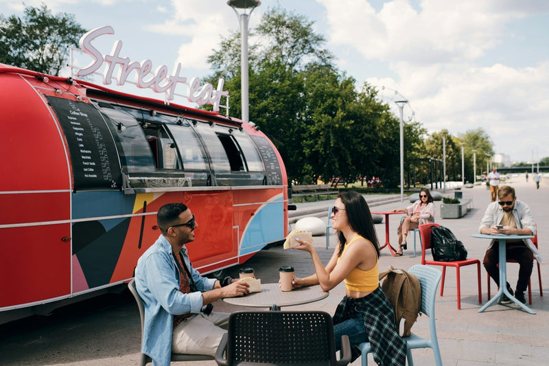 Customers enjoying food at colorful food truck parked outdoors on a sunny day