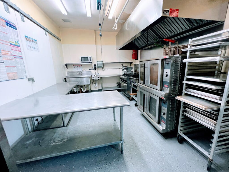 Commercial ghost kitchen with stainless steel equipment and ventilation system, ready for rental use