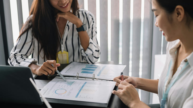 Two women reviewing rental options and costs for a commercial kitchen in a business setting