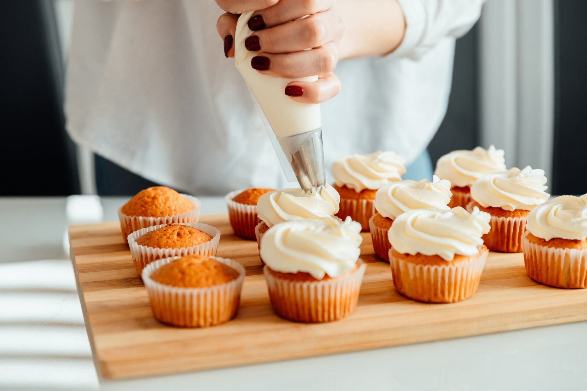 Cupcakes with frosting being piped, used as background image for FAQs section.