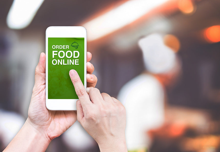 A woman holding a clipboard and checking inventory on grocery store shelves — representing preparation and organization in an online food business.