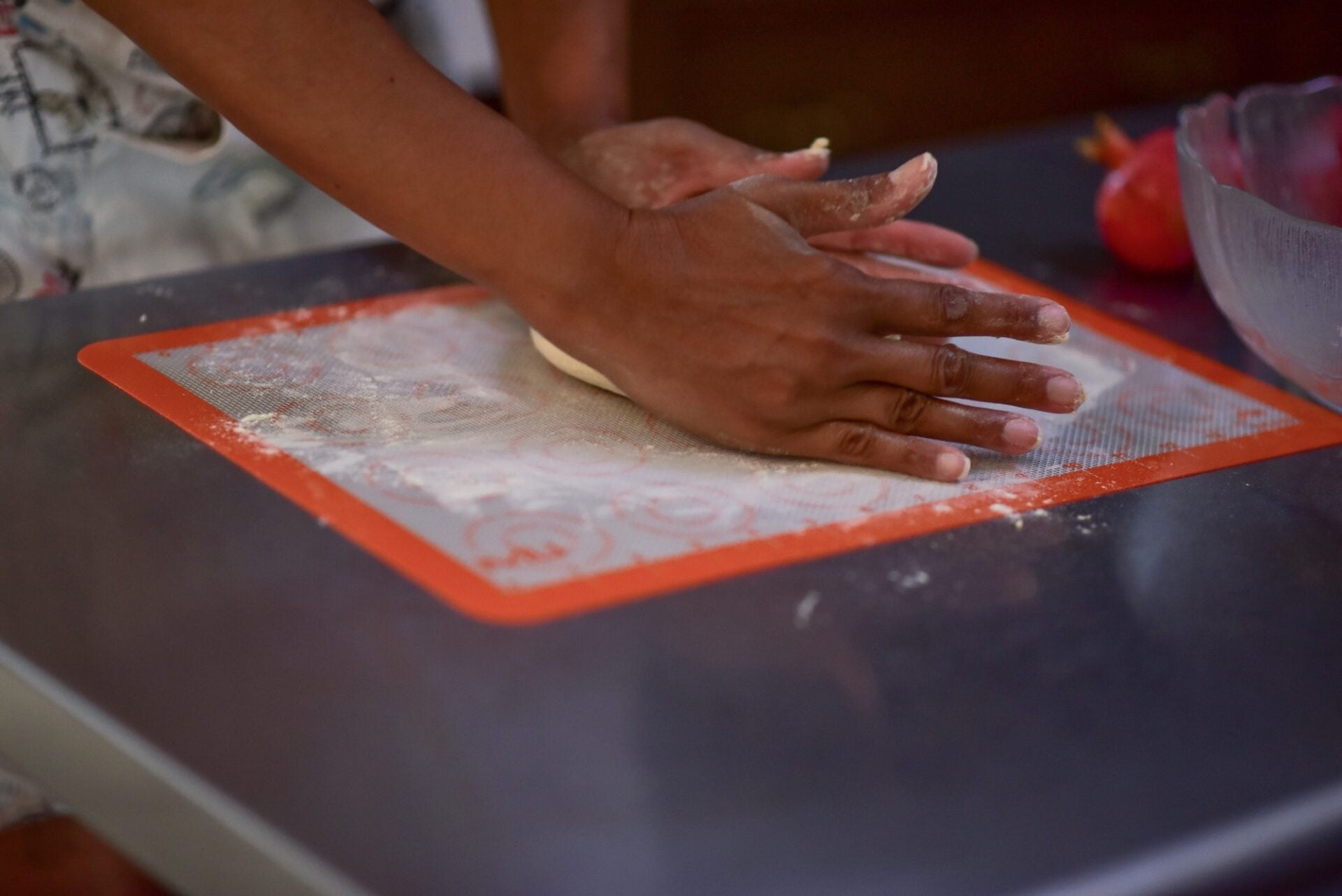 Hands kneading dough on a silicone baking mat